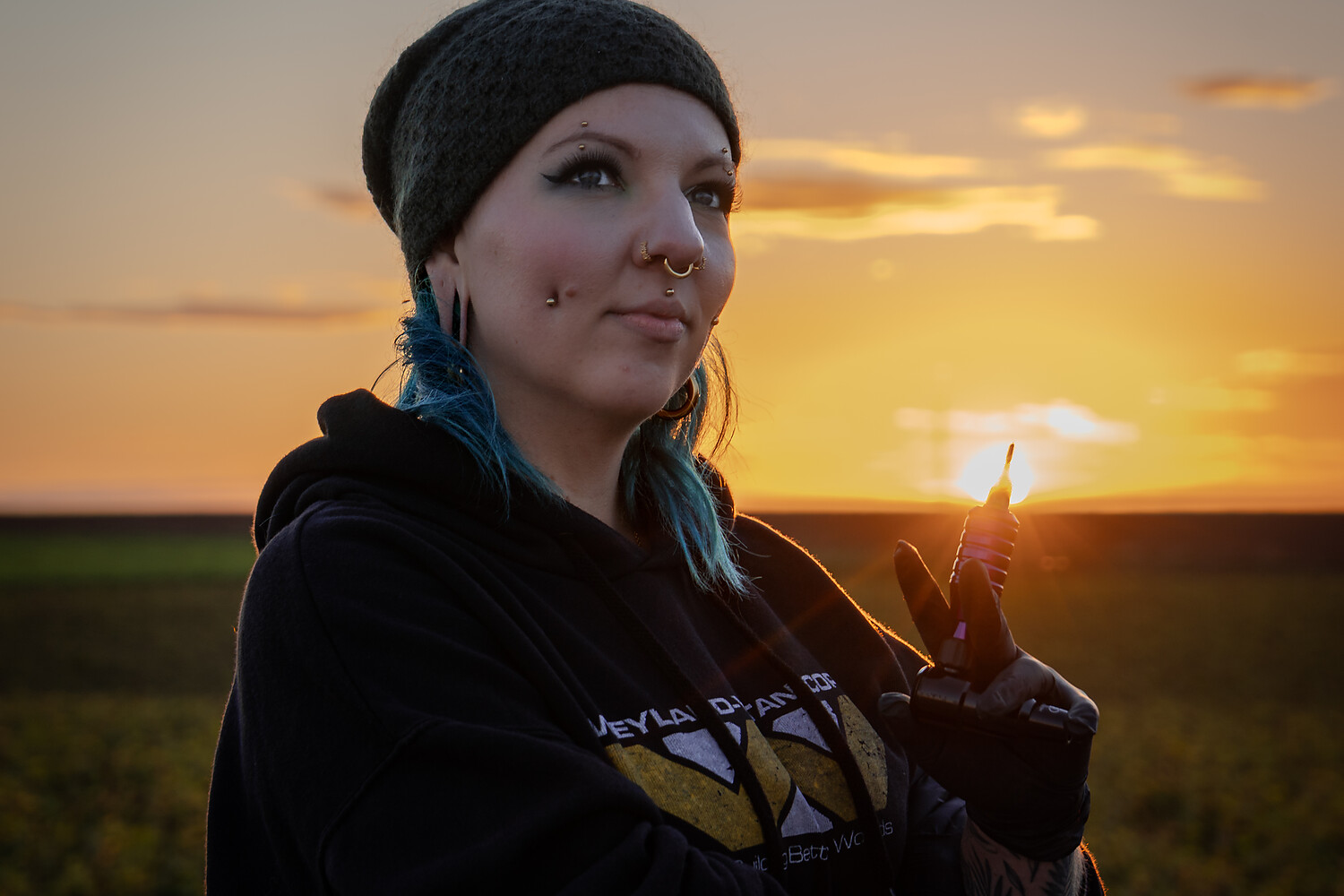 Golden-hour portrait of Sophie Guiot (Spooky So), tattoo artist, near a wind turbine in Hesbaye